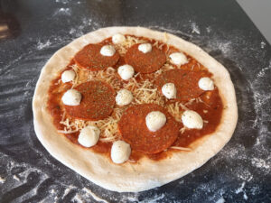 Foto van een vers belegde pizza Diavola voordat deze de oven in gaat