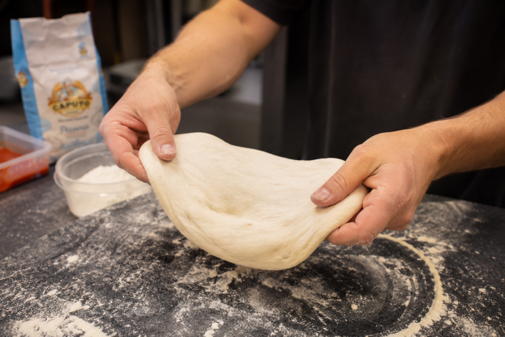 foto van pizzadeeg dat krimpt tijdens het uitrekken
